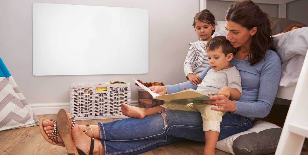Frau liest 2 Kindern aus einem Buch vor, im Hintergrund ist ein infrarotpaneel zu sehen